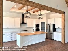 an open kitchen with white cabinets and wood flooring is pictured in this image, there are three pendant lights hanging from the ceiling