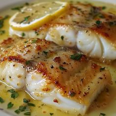 two fish fillets with lemon sauce on a white plate