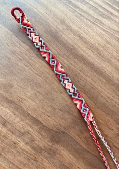 a red, white and blue lanyard on a wooden table next to a pair of scissors