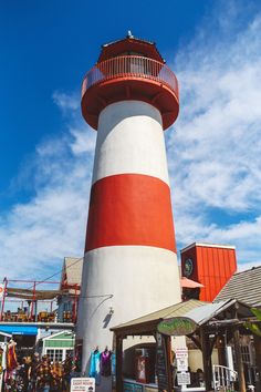 a red and white lighthouse with people walking around it