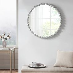 a living room with white walls and a round mirror on the wall above a bench