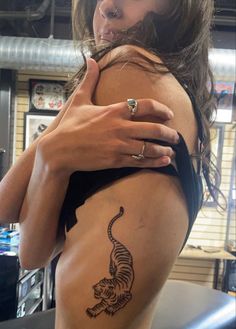 a woman with a tiger tattoo on her back holding onto the side of her body