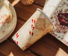 a paper cup sitting on top of a wooden table next to other plates and cups