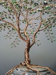 a wire tree sculpture with green beads on it's branches and the roots wrapped in twine