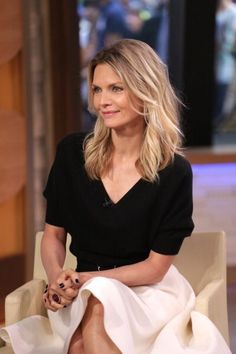 a woman sitting on top of a white chair in front of a tv screen with her legs crossed