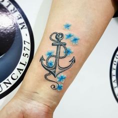 an anchor tattoo with blue flowers on the wrist