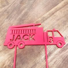 a red paper cut out of a truck on top of a wooden table with the word jack written in it