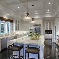 a large kitchen with an island in the middle and two stools at the end