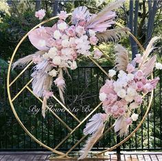 a wreath with flowers and feathers on it in front of a gate that says, by nature to go