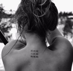 the back of a woman's neck with numbers tattooed on her upper and lower back