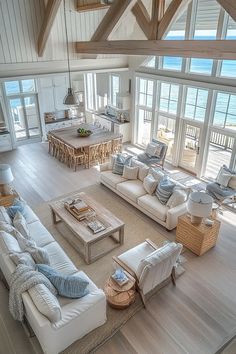 a living room filled with lots of furniture and large windows overlooking the ocean on top of a wooden floor