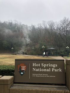 the hot springs national park sign is in front of some bushes and trees with fog