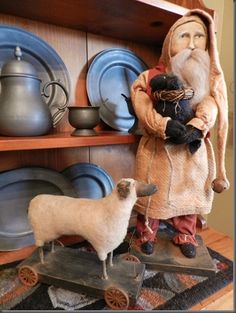 a statue of an old man holding a doll next to a sheep on a table