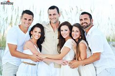 a group of people standing next to each other in front of tall grass and sea oats