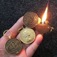 a person holding three different types of coin key chains in their hand, with a lit candle behind them