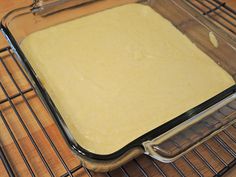 a pan filled with batter sitting on top of a metal rack next to a wooden table