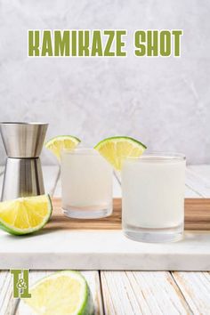 two shot glasses with limes and a cocktail shaker next to them on a cutting board