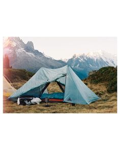 a blue tent sitting on top of a grass covered field