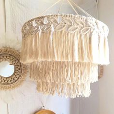 a white lamp hanging from the ceiling next to a basket with flowers on it and a mirror