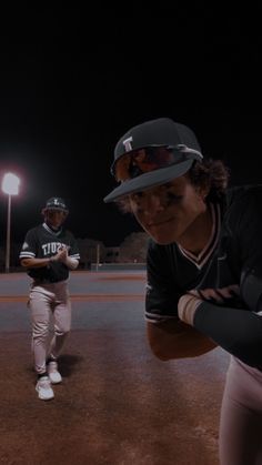 two baseball players standing on the field at night