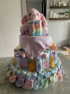 a diaper cake with a teddy bear sitting on it's top and lots of baby items