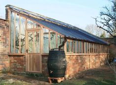 an old barrel sitting in front of a brick building with a solar panel on the roof