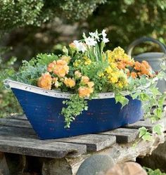 a blue planter filled with flowers sitting on top of a wooden table