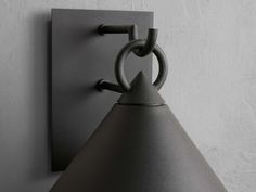 a wall light that is on the side of a wall with a black shade hanging from it