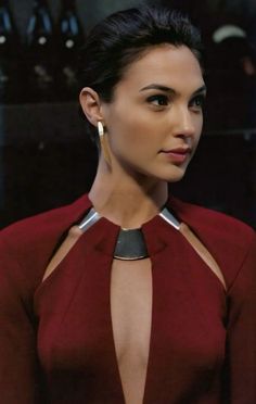 a woman in a red dress with silver accents on her neck and chest is looking at the camera