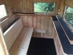 the inside of a small wooden building with benches and windows on each side of it