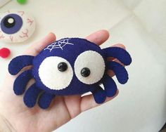 a hand holding a blue and white stuffed animal with eyes on it's face