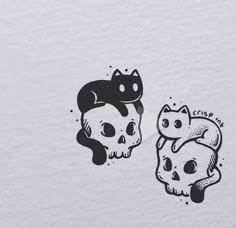 two stickers depicting cats and skulls on a white paper background, one with black cat's head in the middle