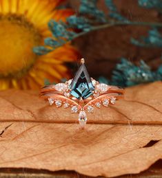 a blue diamond ring sitting on top of a leaf next to a yellow sunflower