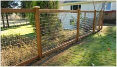 a fence that has grass growing on top of it and some bushes in the back