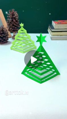 an origami christmas tree on a table with pine cones