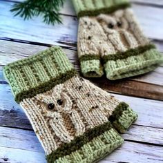 two knitted mittens sitting on top of a wooden table next to a pine tree