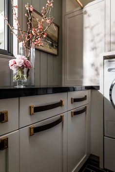 a vase with flowers on top of a counter next to a washer and dryer