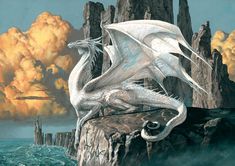 a white dragon sitting on top of a rock next to the ocean with clouds in the background