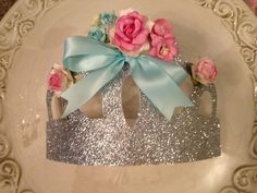 a white plate topped with a pink and blue flowered crown on top of it