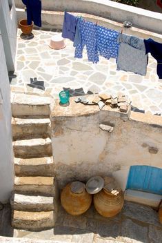 clothes hanging out to dry in the sun on a stone patio with blue doors and steps