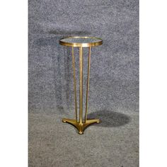 a gold plated metal and glass side table on grey carpeted floor with gray background