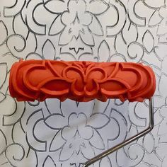 a red object is sitting on a metal rack with an intricate design behind it, against a white wall