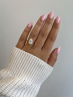 a woman's hand with pink manicured nails and a diamond ring