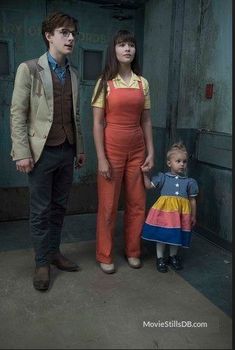 two people and a small child standing in front of a door