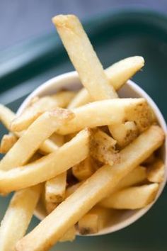 french fries are in a white bowl on a table