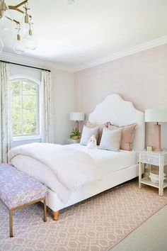 a white bed sitting next to a window in a room with pink carpet and curtains