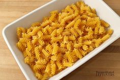 a white bowl filled with pasta on top of a wooden table