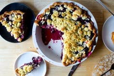 a pie with blueberries and crumbled toppings sits on a wooden table