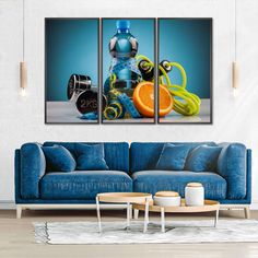 a living room with blue couches and three paintings on the wall, one has an orange in front of it