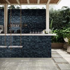 an outdoor bar with blue tiles and plants in the backgrounge, next to a pool